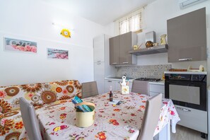 Une cuisine compacte comprenant un coin repas, un canapé et une table recouverte d’une nappe à motifs floraux.