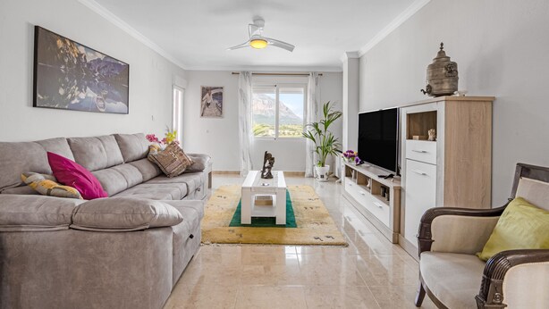 Una sala de estar con un sofá, una mesa de centro, un televisor y un aparador.