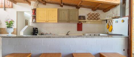 Une cuisine avec des meubles en bois, un plan de travail en granit et quatre tabourets en bois.