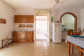 A kitchen with wooden cabinets, a refrigerator, and a dining table with a patterned tablecloth.