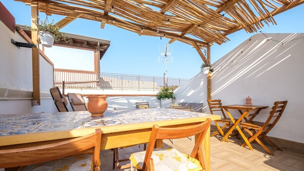A wooden pergola with a tiled table and chairs, a potted plant, and a view of the sky. - Holiday Home 'Mira' accomodation with a terrace. (Spadafora)