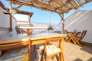 A wooden pergola with a tiled table and chairs, a potted plant, and a view of the sky. - Holiday Home 'Mira' accomodation with a terrace. (Spadafora)