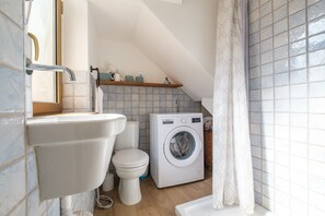 A compact bathroom with a sink, toilet, and washing machine. - Holiday Home 'Mira' accomodation with a terrace. (Spadafora)