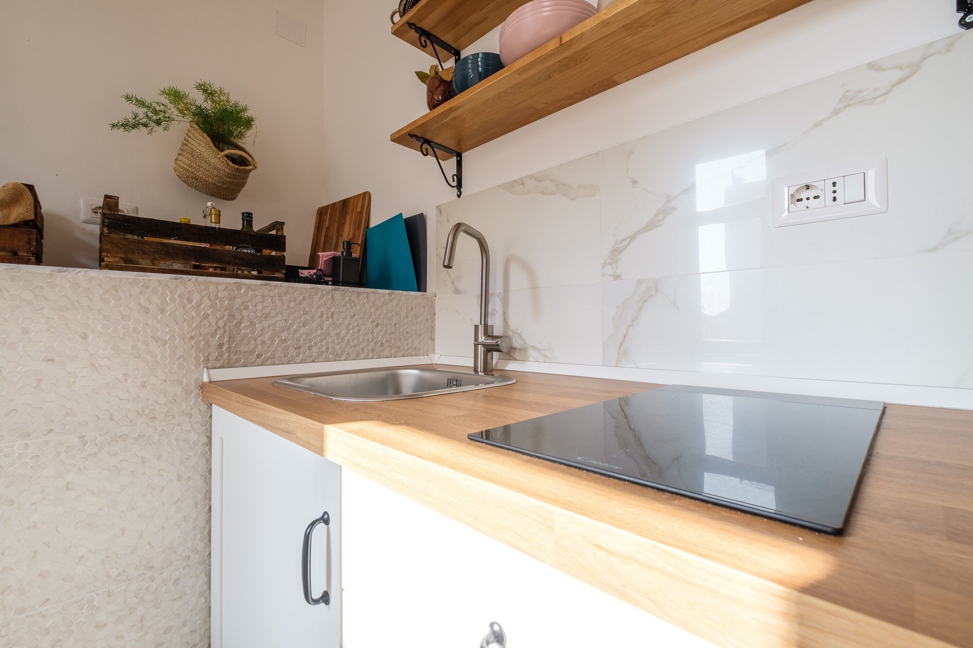 A kitchen with a wooden countertop, a stainless steel sink, a built-in stove, and a hanging plant.