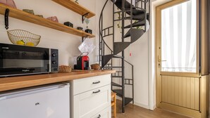 A kitchen with a microwave, refrigerator, wooden shelves, a basket, and a spiral staircase. - Holiday Home 'Mira' accomodation with a terrace. (Spadafora)
