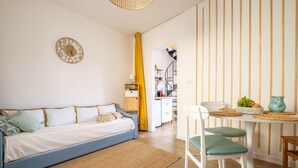 A modern bedroom with a bed, a wall clock, and a kitchen area with a dining table and chairs. - Holiday Home 'Mira' accomodation with a terrace. (Spadafora)