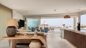 Una sala de estar moderna con un ventanal grande, una mesa de centro de madera, un sofá y una zona de bar.