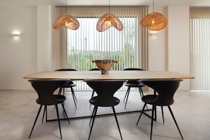 A modern dining area with a wooden table, black chairs, and woven pendant lights.