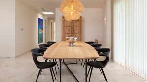 Un comedor moderno con una mesa de madera, sillas negras, un bol central y una lámpara de fibra.