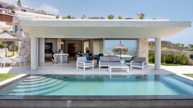 Una casa moderna con piscina, mobiliario de exterior y vistas del paisaje circundante.