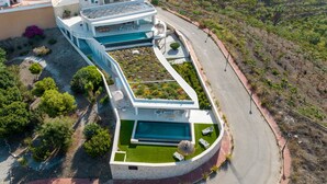 Una villa moderna con piscina, camino de entrada curvo y jardín ajardinado.