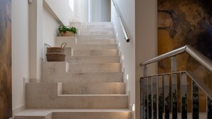 Eine Treppe mit Metallgeländer, einem gewebten Korb und einem Blumentopf auf dem Podest.