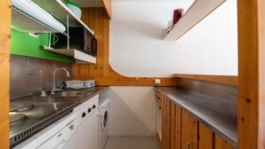 Uma cozinha compacta com fogão, pia e máquina de lavar.