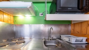 Cozinha em aço inoxidável com micro-ondas, pia e escorredor de louça.