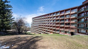 Un hôtel à plusieurs étages doté de balcons, d’une pelouse et d’arbres.