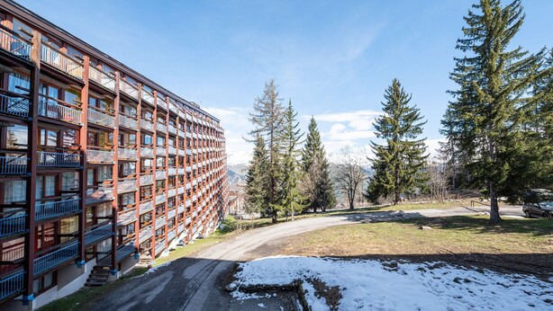 Un hôtel à plusieurs étages doté de balcons, d’un parking et d’un terrain enneigé.