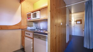 Une cuisine de taille réduite, dotée de meubles en bois, d’un four à micro-ondes, d’une cuisinière et d’un lave-vaisselle.