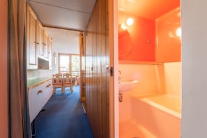 Kapea käytävä johtaa kylpyhuoneeseen, jossa on pesuallas ja kylpyamme.