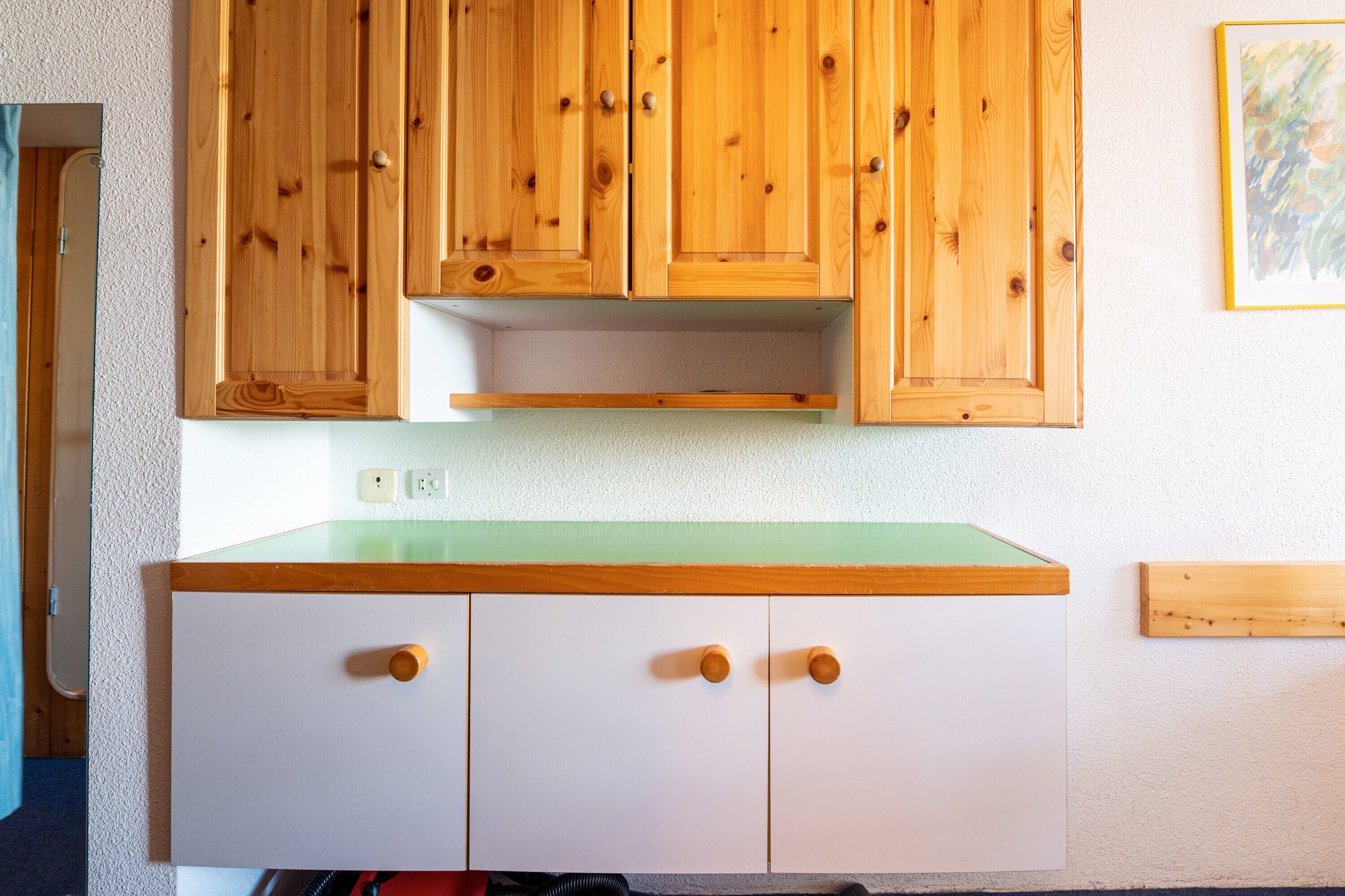 Een keuken met houten kastjes, een wit aanrechtblad en een groene spatwand.
