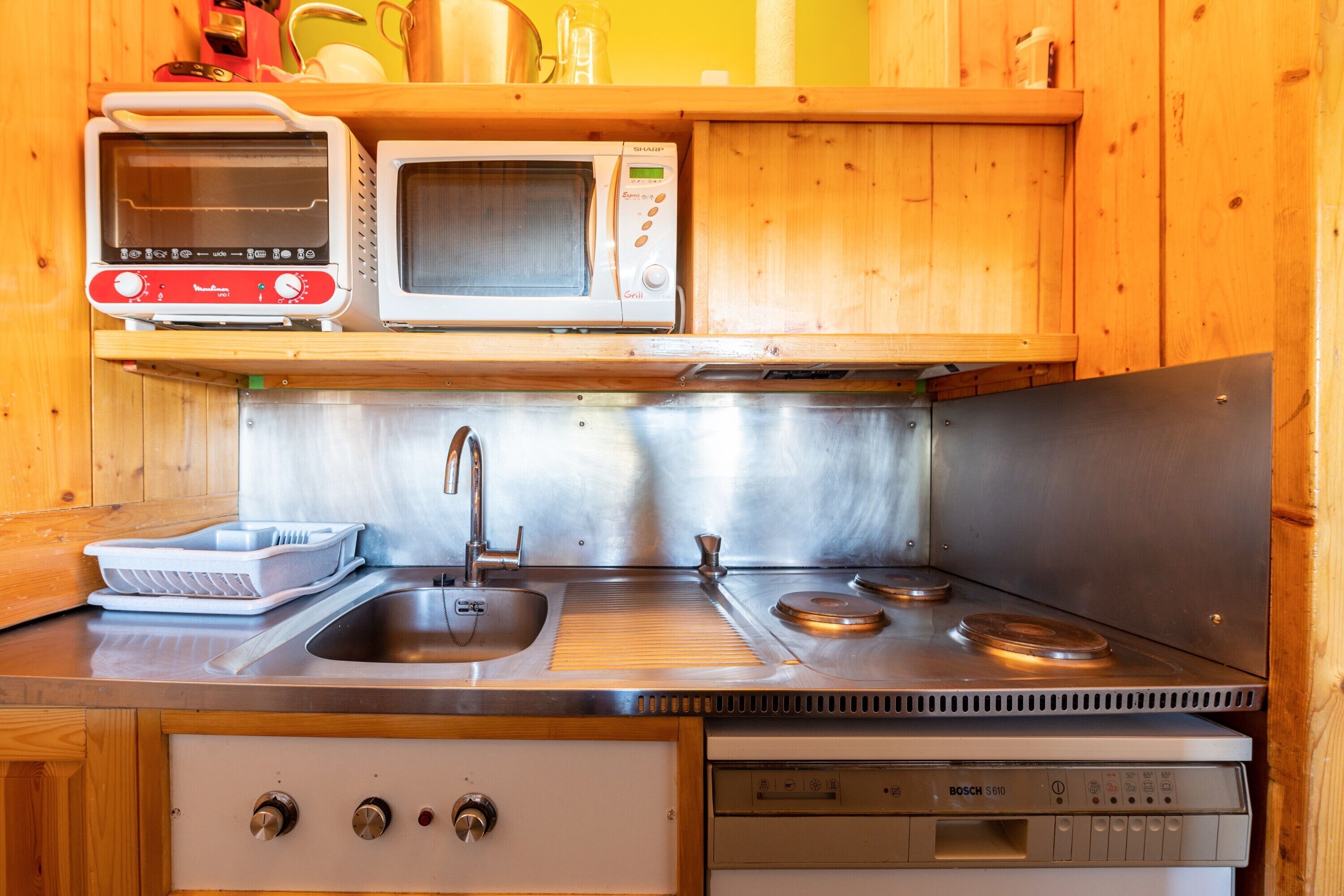 A compact kitchen with a sink, two ovens, and a dishwasher.