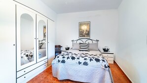 Una camera da letto con un letto, un comodino, una cassettiera con specchi e un quadro appeso al muro.