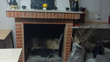 A kitchen with a brick fireplace, a clock, and various kitchen items on the counter.