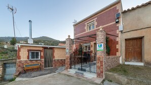 Un edificio residenziale con ingresso recintato, un camino e una panchina all'esterno.