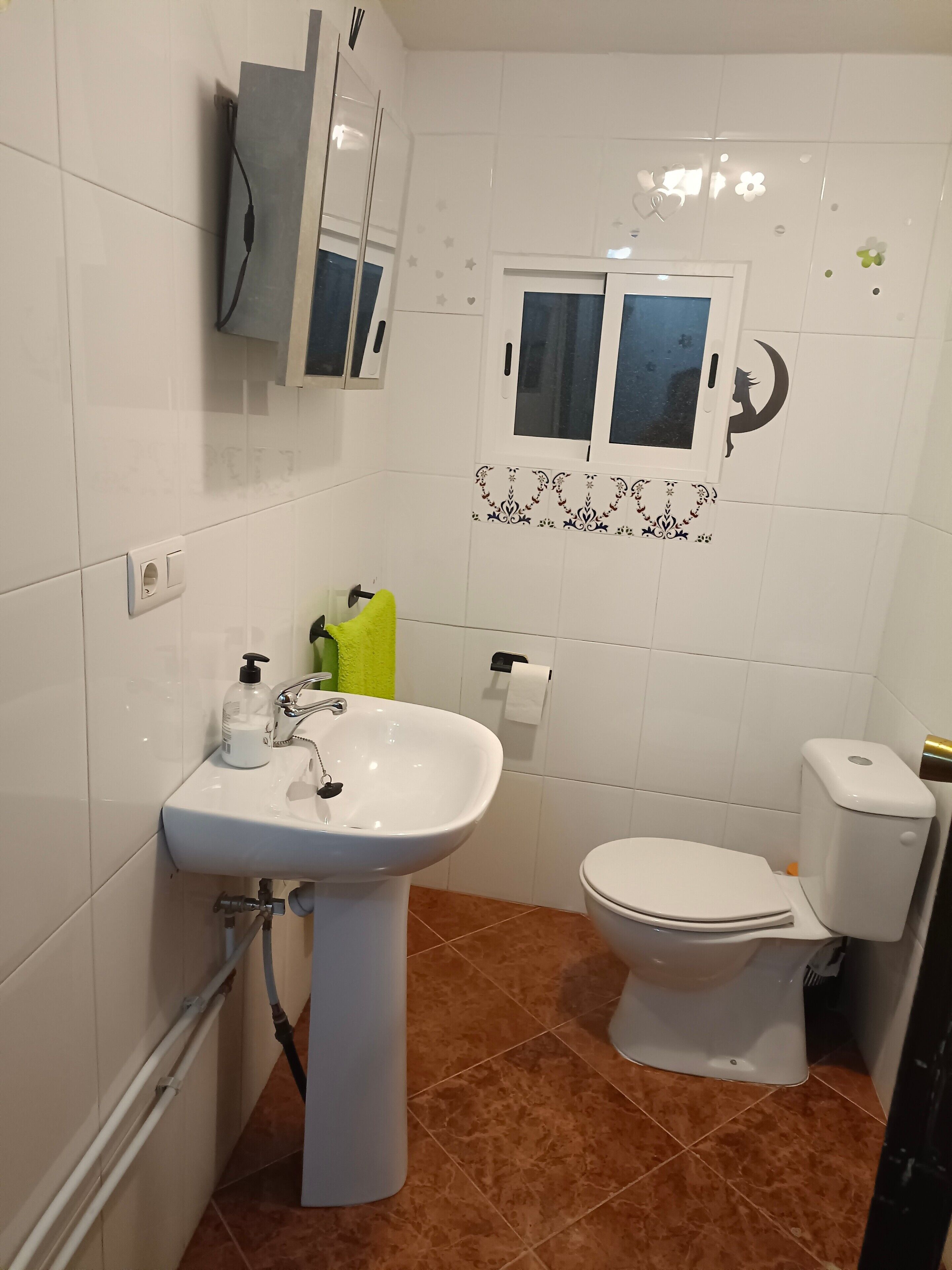 Un baño con lavamanos, inodoro y espejo blancos.