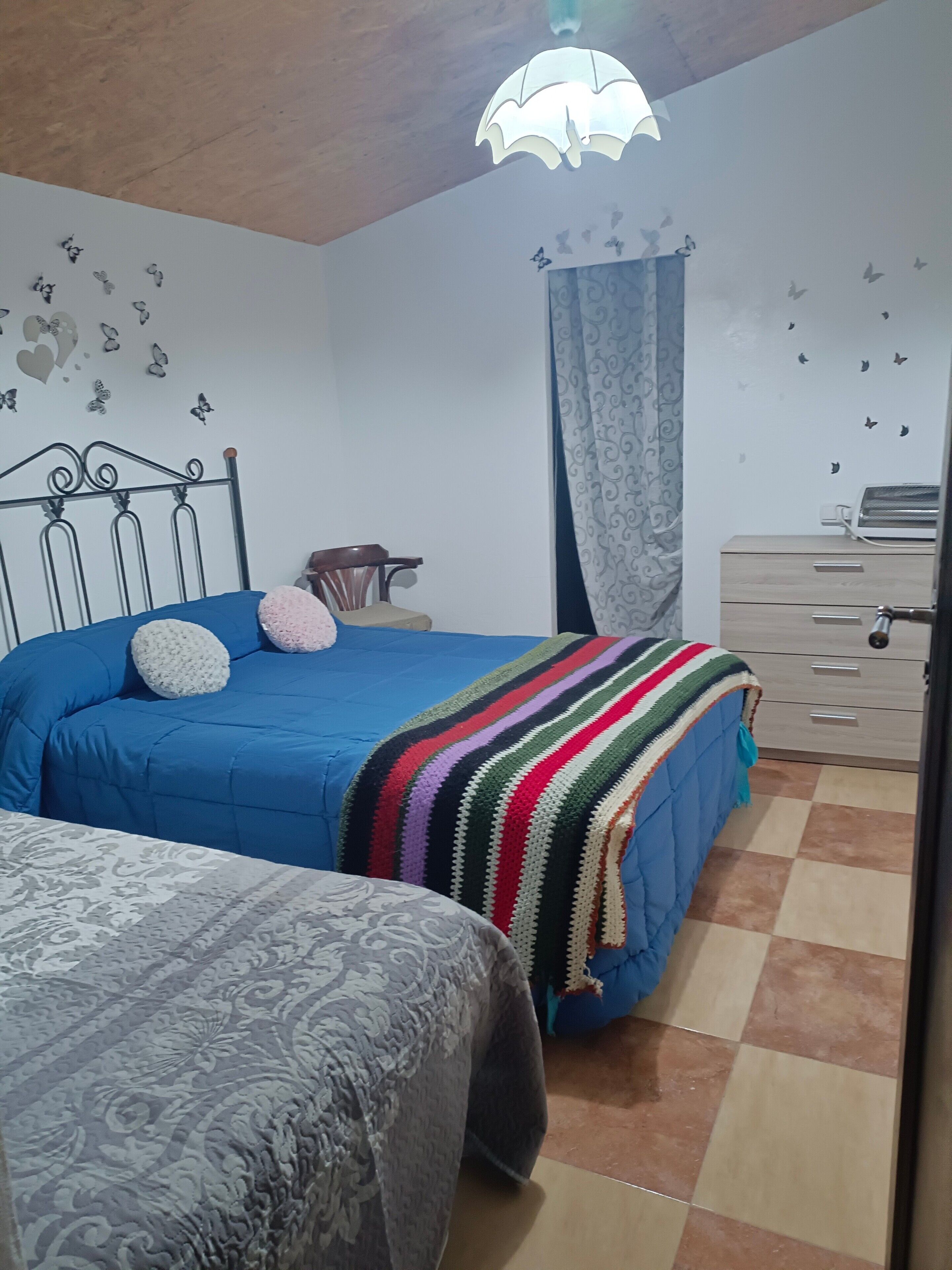 Quarto com cama, cadeira, cômoda e tapete estampado.