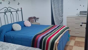 Quarto com cama, cadeira, cômoda e tapete estampado.