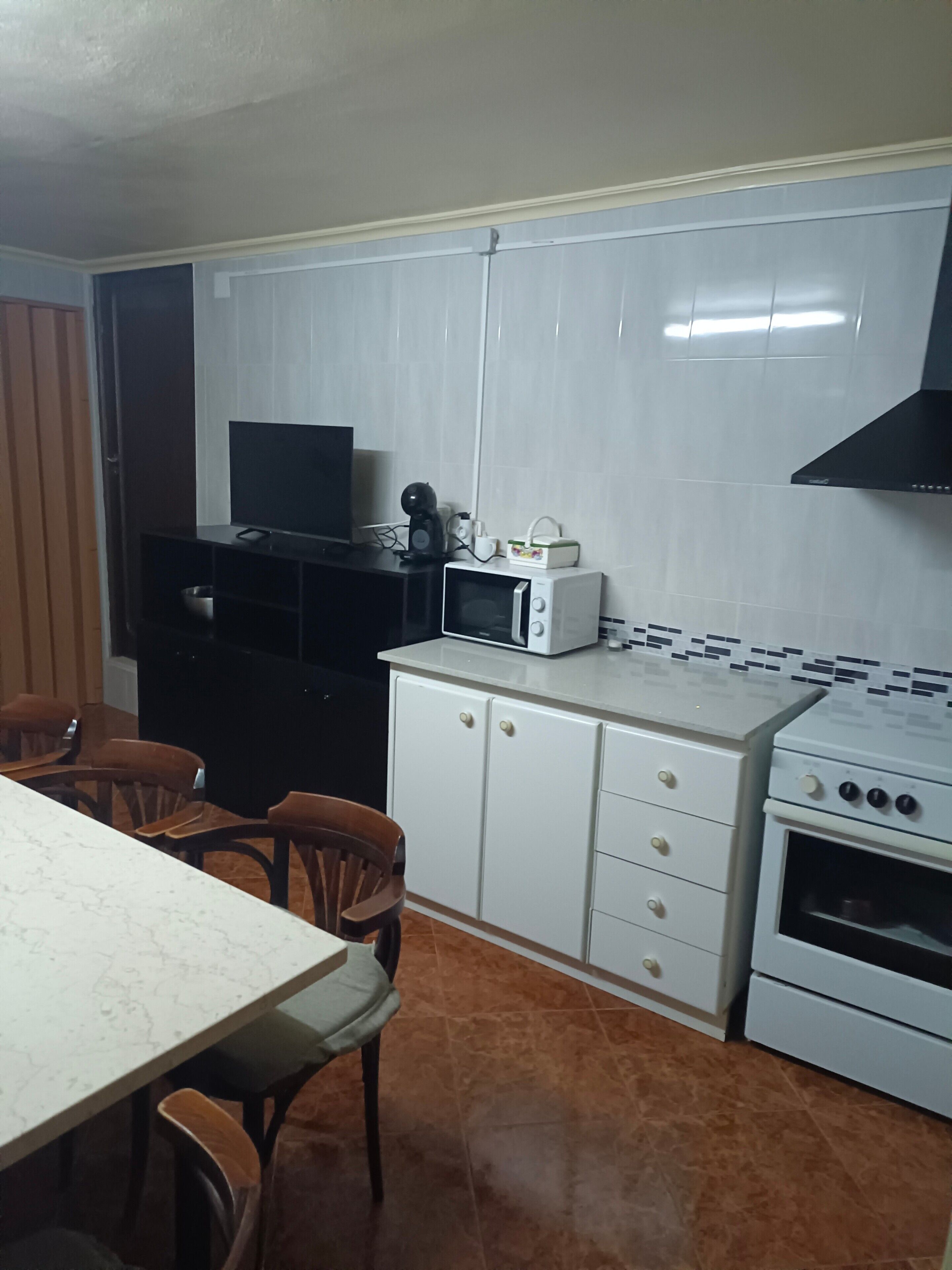 Une cuisine équipée d’un four à micro-ondes, d’une cuisinière, de placards et d’un coin repas avec des chaises et une table.
