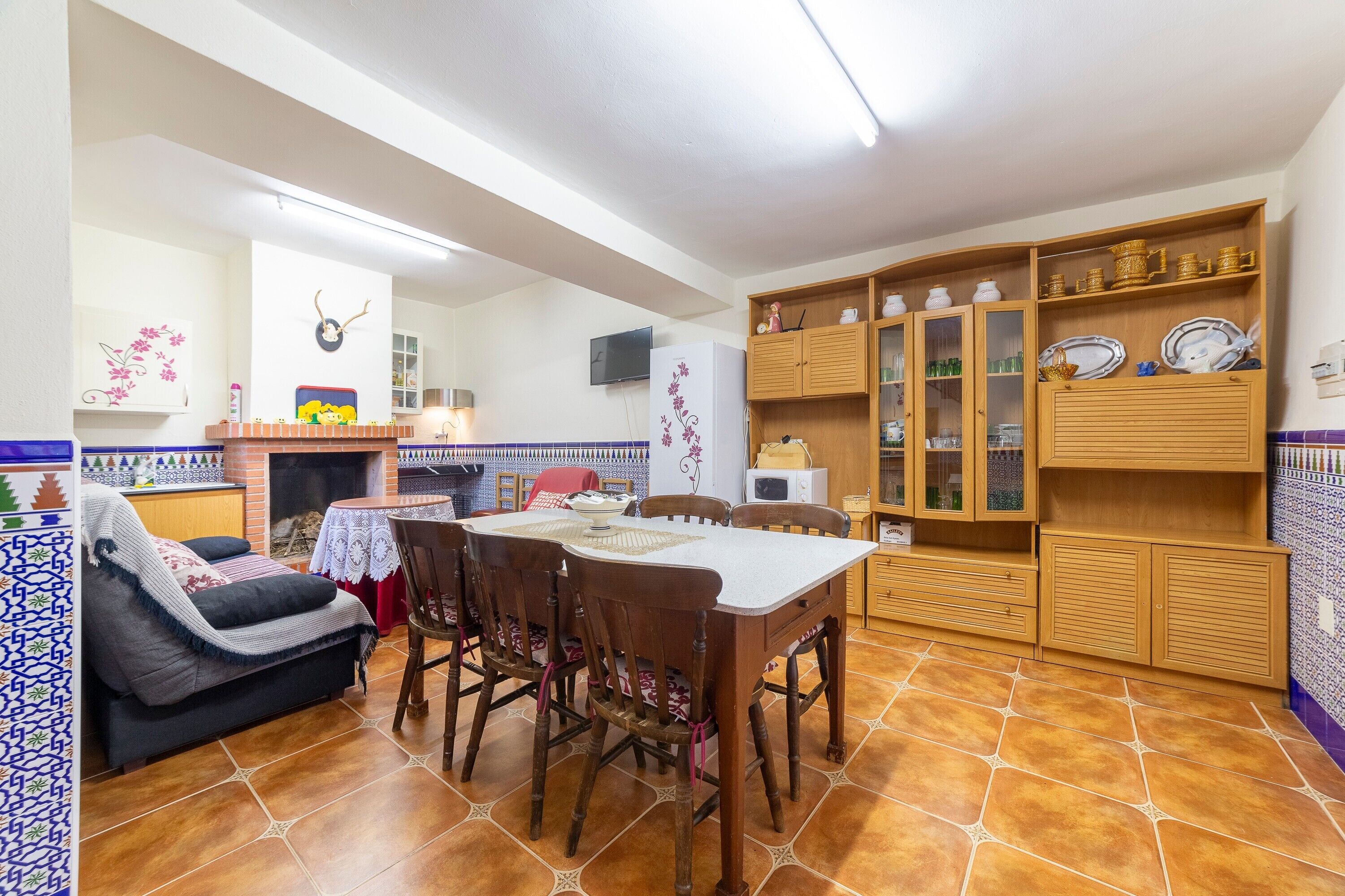 Una cocina acogedora con una mesa de comedor, sillas, un sofá y armarios de madera con puertas de cristal.