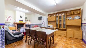 Una cocina acogedora con una mesa de comedor, sillas, un sofá y armarios de madera con puertas de cristal.