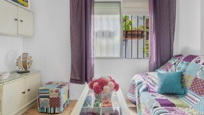 Een kamer met een bed, een klein tafeltje met een bloemenvaas, een kast en een raam met gordijnen.