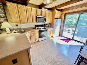 A kitchen with wooden cabinets, a microwave, a stove, and a refrigerator.