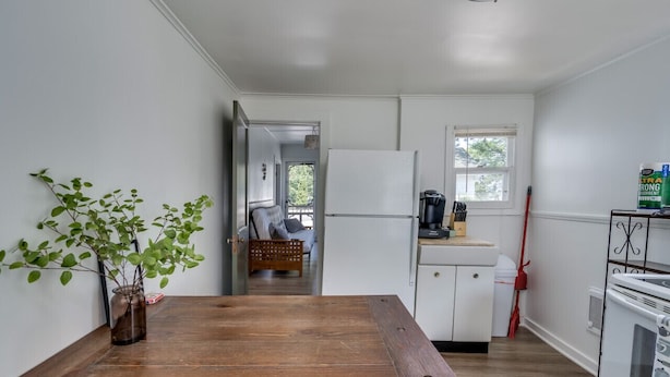A kitchen with white cabinets, a refrigerator, a stove, and a window. - K's Motel - Fishermans Retreat - Cottage (Clayton)