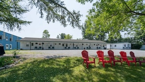 A motel with a row of red chairs in the front lawn and a building with multiple windows and a flat roof. - K's Motel - Fishermans Retreat - Cottage (Clayton)