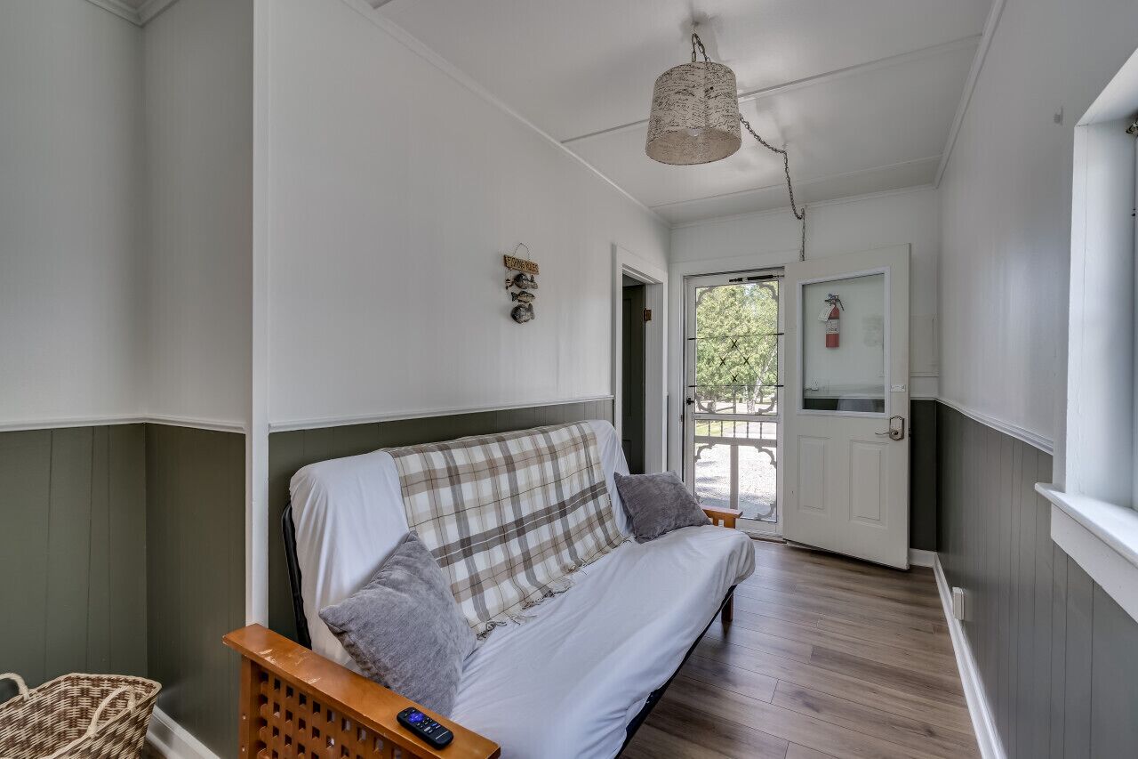 A room with a sofa, a wicker chair, a basket, and a hanging light fixture.