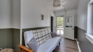 A room with a sofa, a wicker chair, a basket, and a hanging light fixture. - K's Motel - Fishermans Retreat - Cottage (Clayton)