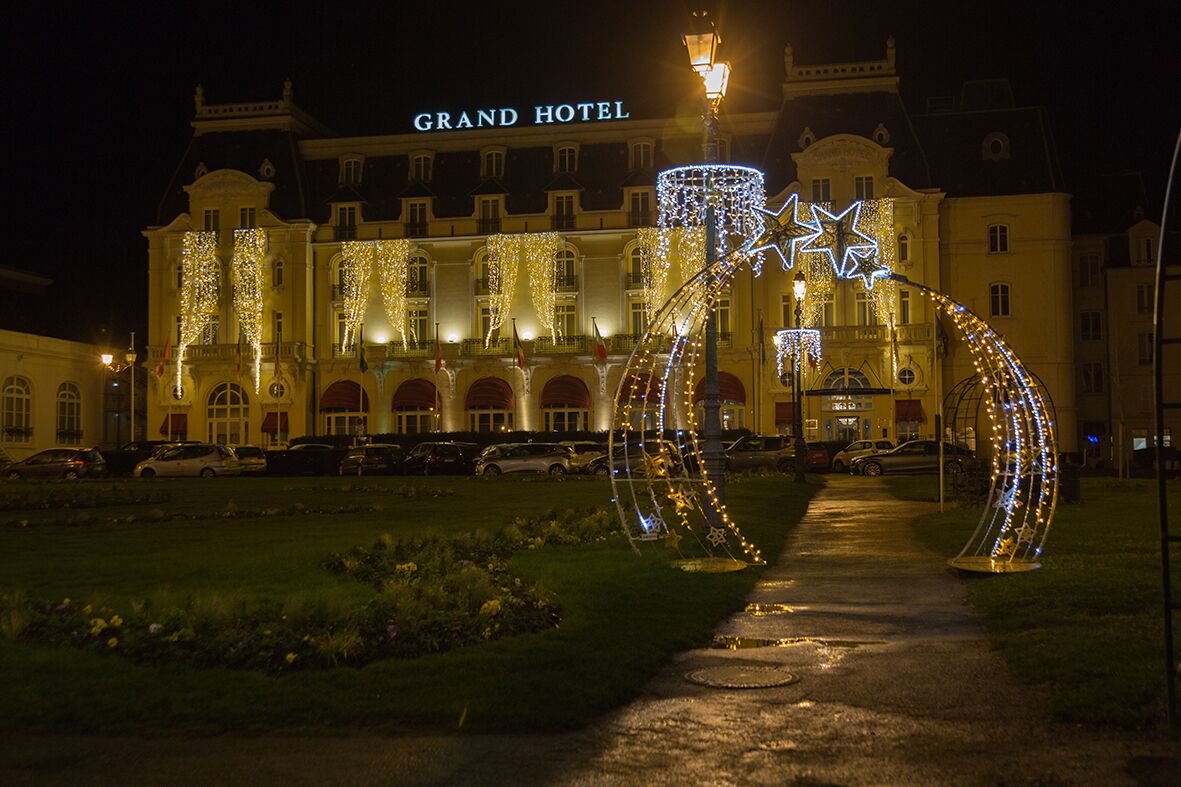 A grand hotel with a prominent entrance, illuminated by decorative lights and a star-shaped structure.