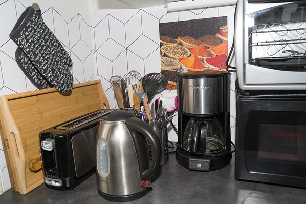 A kitchen with a toaster, kettle, coffee maker, and a microwave.