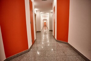 Stylish corridor with speckled tile flooring and white doors leading to a room.