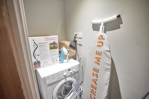 Convenient laundry area with a washing machine, drying rack, and essentials.