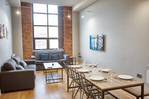 Una sala de estar moderna con comedor, un sofá, una mesita de centro y una pared de ladrillo.