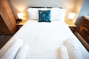 Restful retreat with a neatly made bed, bedside lamps, and a brick accent wall.