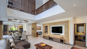 A spacious living area with a large sofa, a coffee table, and a TV wall unit. - Villa UmaDahayu (Denpasar)