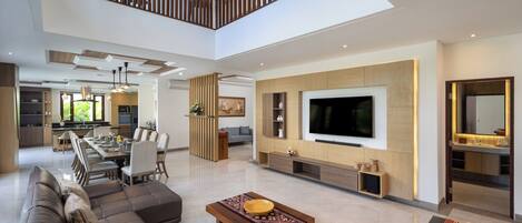 A spacious living area with a large sofa, a coffee table, and a TV wall unit.