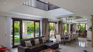 A spacious living area with a large sectional sofa, a dining table with chairs, and a kitchen in the background. - Villa UmaDahayu (Denpasar)