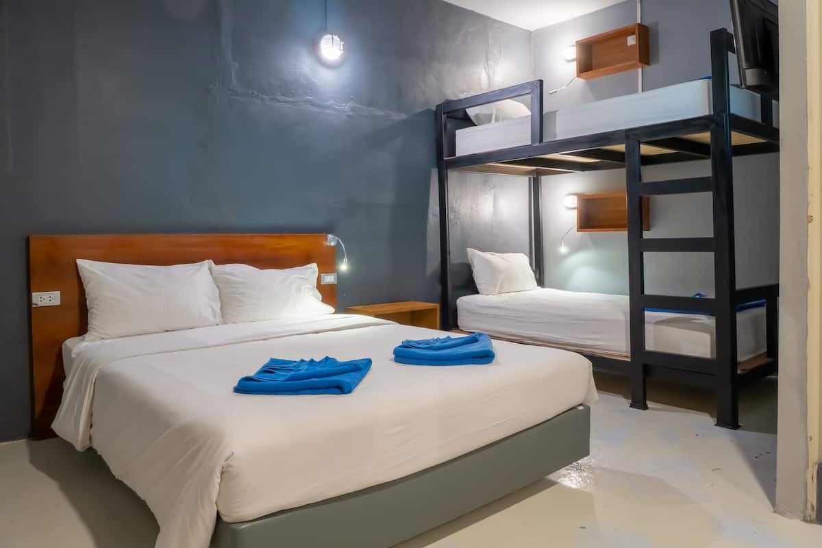 A hotel room with a bunk bed, a single bed, and a nightstand.