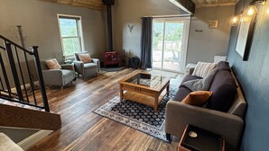 Ein geräumiges Wohnzimmer mit Holzboden, einem Glastisch und einer Couch.